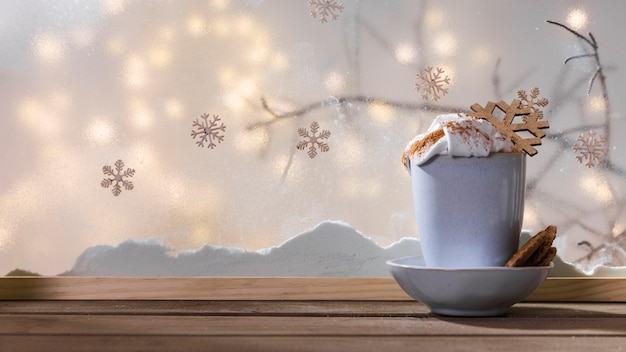 Caneca com floco de neve de brinquedo na placa com cookies na mesa de madeira perto de banco de neve e luzes de fada Foto gratuita