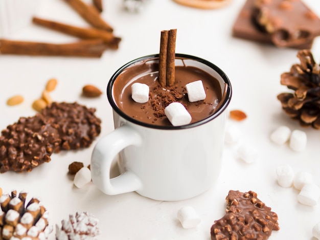 Caneca esmaltada de chocolate quente com canela e marshmallows Foto gratuita