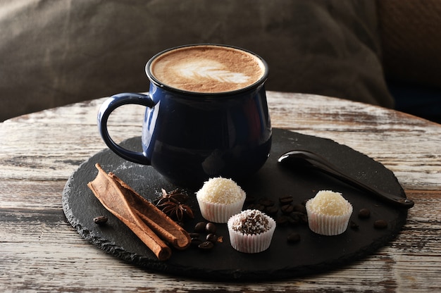 Cappuccino em uma caneca, canela e cupcakes com creme e chocolate Foto Premium