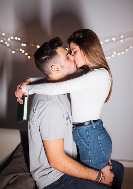 Cara jovem, beijando e abraçando a senhora com um livro no sofá Foto gratuita