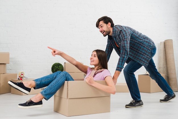 Casal feliz está se divertindo com caixas de papelão em casa nova ...