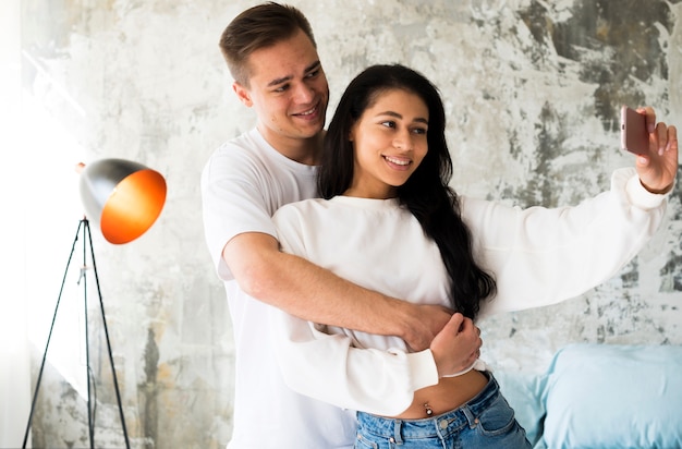 Casal multirracial atraente tendo selfie Foto gratuita