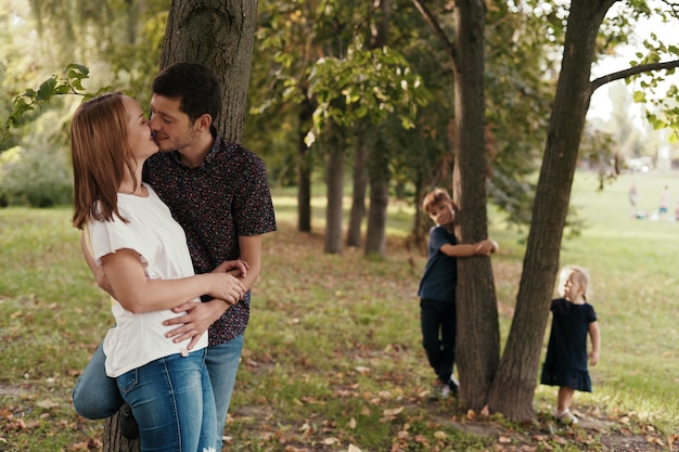 Casal Se Beijando Enquanto Seus Filhos Assistindo Ao Ar Livre Foto Grtis