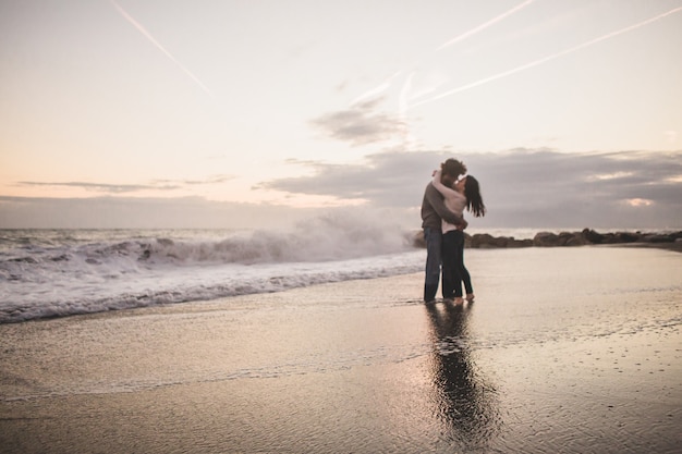 Casal se beijando na costa da praia ao pÃ´r do sol Foto gratuita