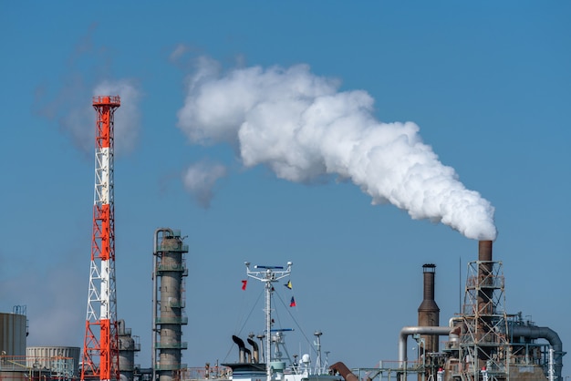 Cena da zona industial da refinaria de petróleo ao lado do rio na hora de funcionamento que têm o fumo de vapor Foto Premium