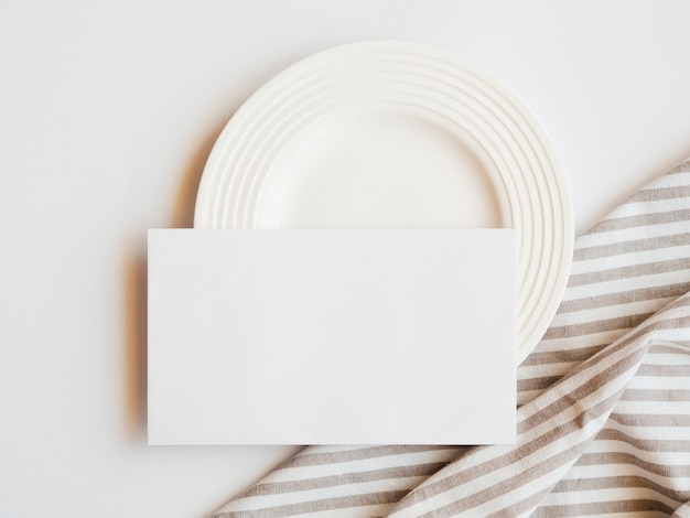 Chapa branca com um espaço em branco branco e uma toalha de mesa marrom e branca listrada em um fundo branco Foto gratuita