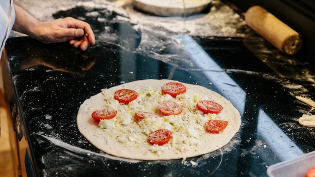 Chef fazendo caprese bianca pizza, adicionando azeite na massa. Foto Premium