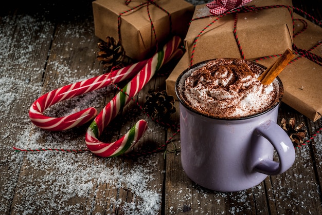 Chocolate quente com chantilly e especiarias, presentes de natal e bastões de doces Foto Premium