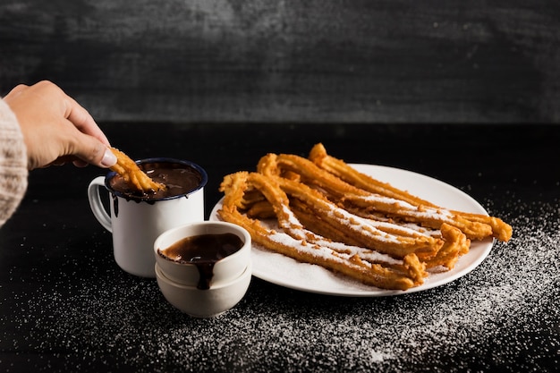 Churros de alta vista em um prato com canecas de chocolate doce Foto gratuita