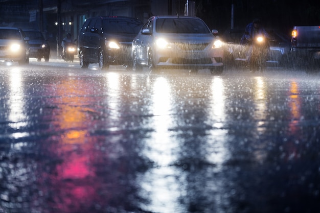 Chuva dura cair à noite com carros embaçados. foco seletivo. Foto Premium