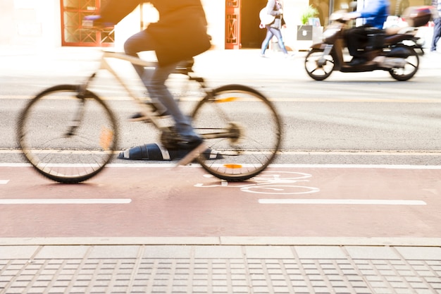 Ciclista irreconhecível, andar de bicicleta na ciclovia pela rua da cidade Foto gratuita