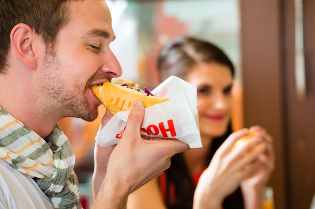 Clientes comendo hotdog na lanchonete fast food Foto Premium