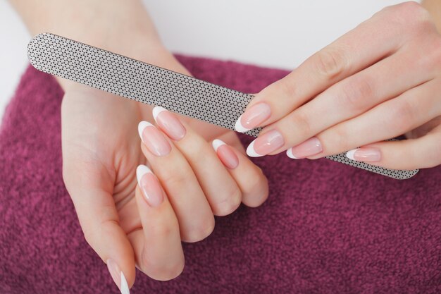 Close up das mãos fêmeas bonitas que têm o tratamento de mãos dos termas no salão de beleza. pregos naturais saudáveis de filing clients do esteticista com arquivo de prego. Foto Premium