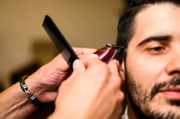 Close-up de barbeiro, dando ao cliente um corte de cabelo Foto gratuita