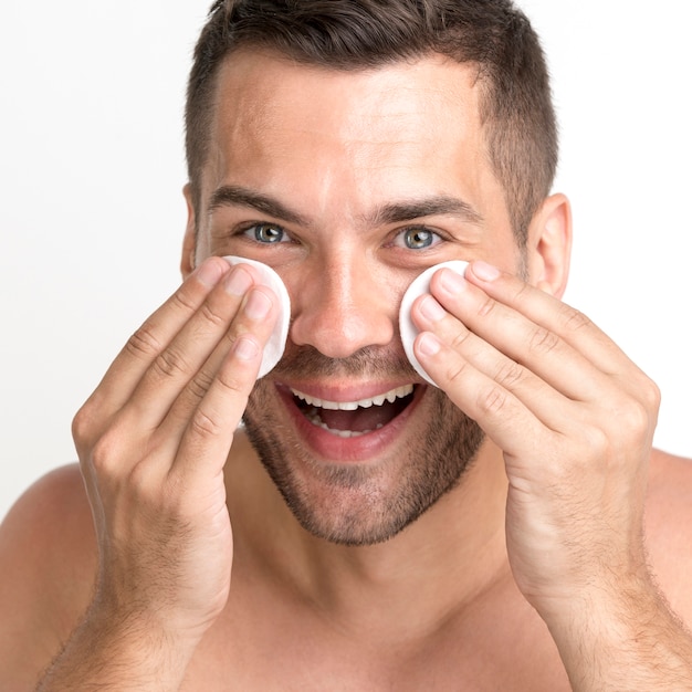 Close-up, de, homem, limpeza, seu, rosto, com, almofada algodão, e, sorrindo Foto gratuita