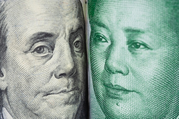 Close up frente a frente de benjamin franklin e de mao tse tung das cédulas do dólar americano e do yuan de china. Foto Premium