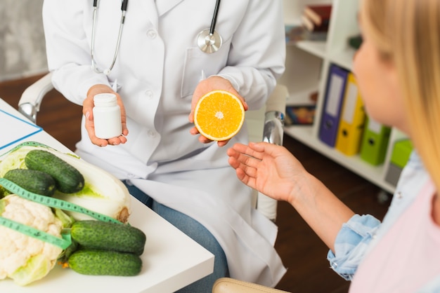 Close-up médico com recipiente de comprimidos e meia laranja Foto gratuita