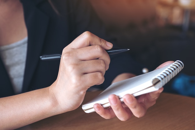 Closeup imagem de uma mão segurando e anotar em um notebook na mesa | Foto  Premium