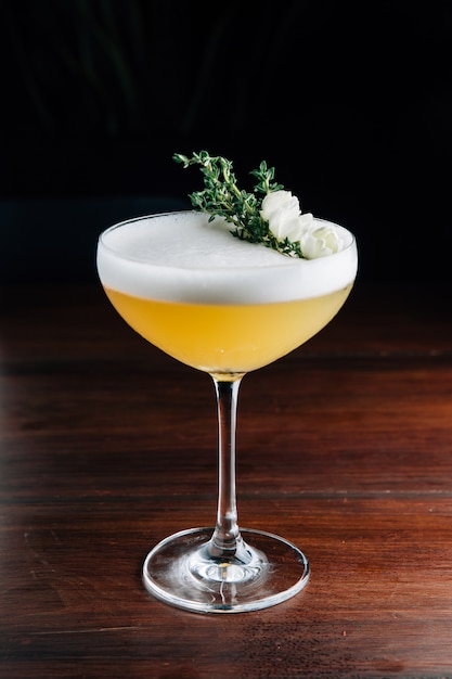  Cocktail  amarelo com a espuma  branca decorada com flor 