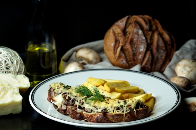 Cogumelo salteado coberto com queijo derretido na torrada, servido com batata frita Foto gratuita