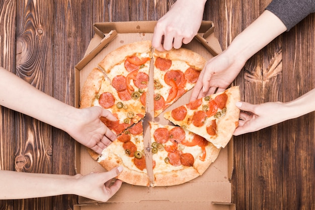 Colheita de mÃ£os tomando pizza Foto gratuita