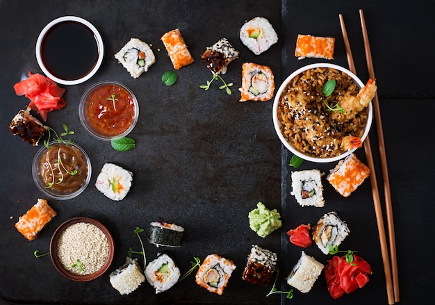 Comida japonesa tradicional - sushi, pãezinhos, arroz com camarão e molho em um fundo escuro. vista do topo Foto gratuita
