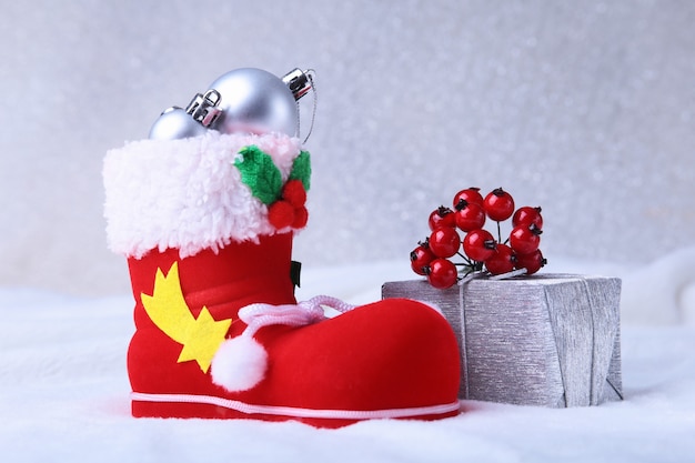 Composição de feliz natal. sapato do papai noel com caixas de presente em penas onduladas com neve e flocos de neve. boas festas Foto Premium