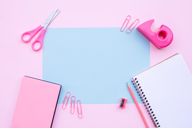 Composição de mesa bonita com notebook, tesoura e livros sobre fundo rosa com blu Foto gratuita