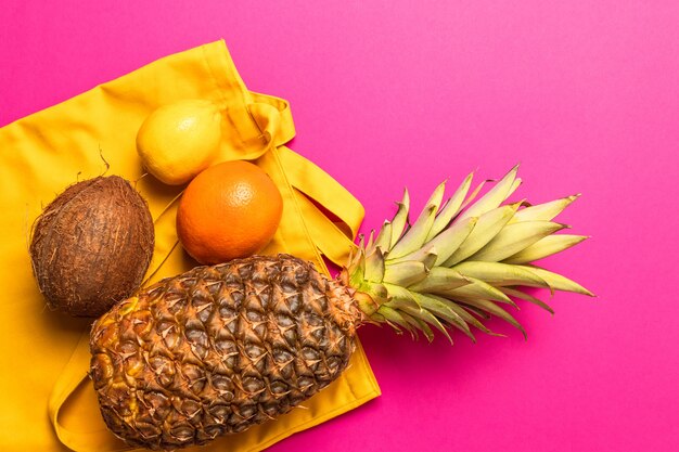 Composição de várias frutas exóticas frescas com um saco de algodão amarelo sobre um fundo amarelo. lay plana. conceito de comida. Foto Premium