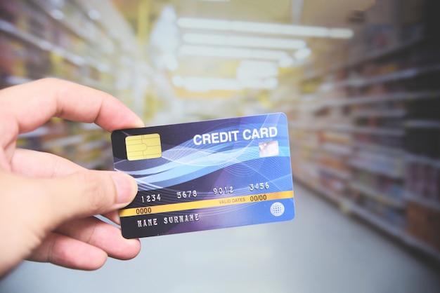 Compras com cartão de crédito no supermercado - mão segurando o pagamento com cartão de crédito Foto Premium