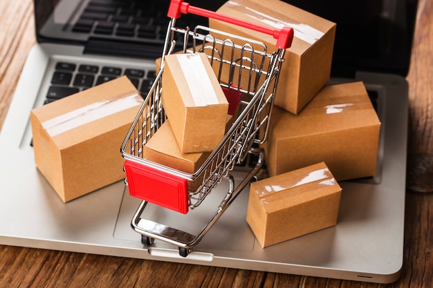 Compras on-line em casa conceito. caixas em um carrinho de compras em um teclado de laptop. Foto Premium