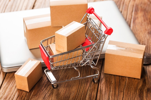 Compras on-line em casa conceito. caixas em um carrinho de compras em um teclado de laptop. Foto Premium