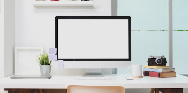 Computador de mesa de tela em branco com material de escritório e mock up frame no local de trabalho moderno Foto Premium