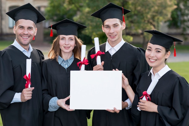 Conceito de formatura com estudantes segurando o modelo de certificado em branco Foto gratuita