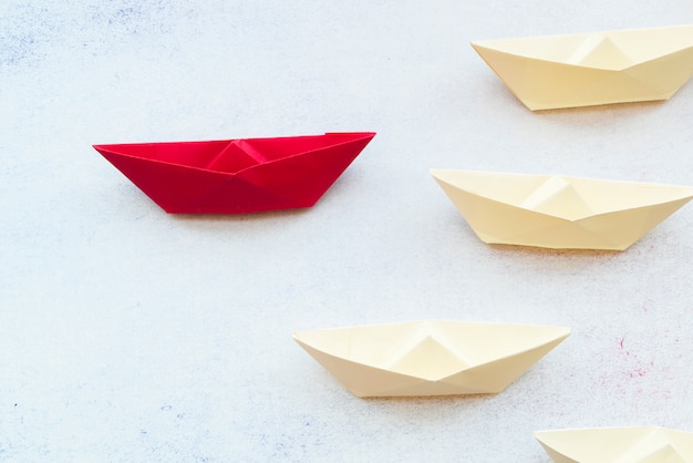 Conceito de liderança, usando o navio de papel vermelho entre branco no pano de fundo Foto gratuita