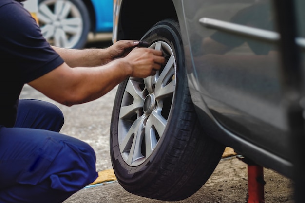 Conceito de substituição de pneus. mecânico que trabalha seu trabalho com roda na garagem. manutenção de carro e serviços Foto Premium