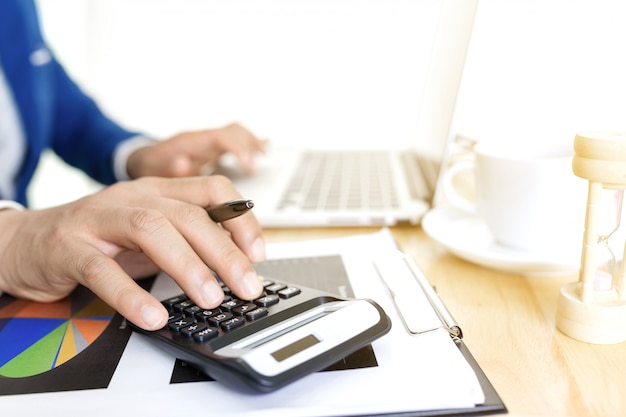 Conceito do plano de contabilidade empresarial, trabalhando no laptop desktop com a calculadora para fazer negócios, mão de homem de negócios trabalhando com o laptop no consultor de investimentos em negócios de mesa de madeira. Foto Premium