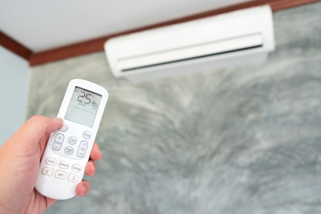 Condicionador de ar dentro da sala com a mulher operando ou fechando o controlador remoto Foto Premium