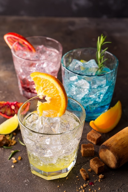 Conjunto de cocktails coloridos com frutas e ervas, açúcar mascavo em fundo de pedra Foto Premium