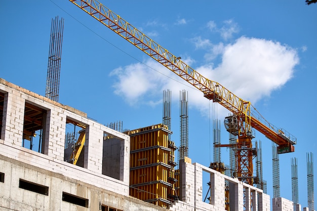 Construção de um edifício alto, a formação de suportes de cimento e o funcionamento de um guindaste contra um céu azul, foco seletivo Foto Premium