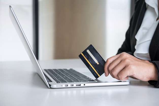 Consumidor de mulher de negócios, mantendo o cartão de crédito e digitando no laptop para compras e pagamentos on-line, faça uma compra na internet, pagamento on-line, redes e compre a tecnologia do produto Foto Premium