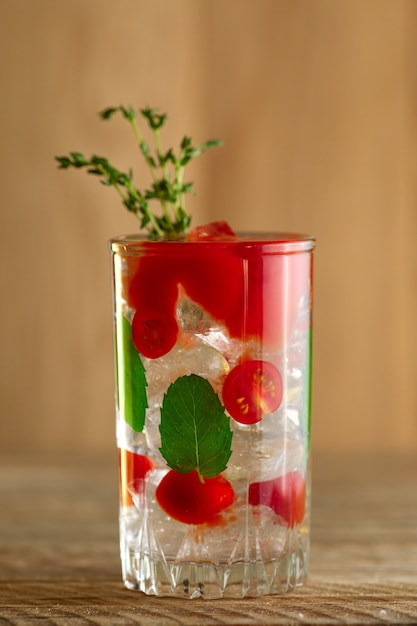 Coquetel com vodka, tomate, hortelã e cubos de gelo na mesa de madeira Foto Premium