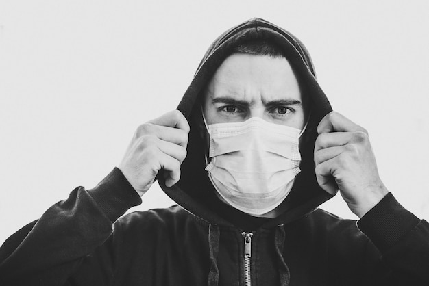 Coronavírus. homem vestindo máscara protetora médica em uma parede.  prevenir covid-19, gripe. sentindo-se mal na cidade. a pessoa precisa de  ajuda. conceito de vírus, pandemia, pânico. foto em preto e branco |