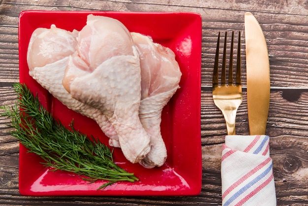 Coxinhas de frango cru com endro fresco no prato com garfo e faca de manteiga Foto gratuita