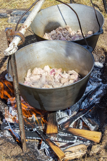Cozinhando o plov no caldeirão. apenas a carne no caldeirão. cozinha de campo. cozinha oriental. Foto Premium