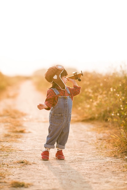 Criança com avião de brinquedo na natureza ao pôr do sol Foto Premium