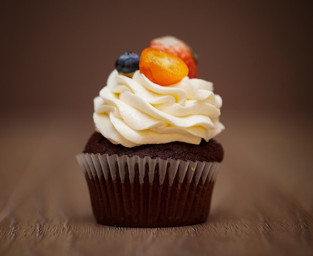 Cupcake de chocolate caseiro com cobertura de chocolate na mesa de madeira Foto Premium