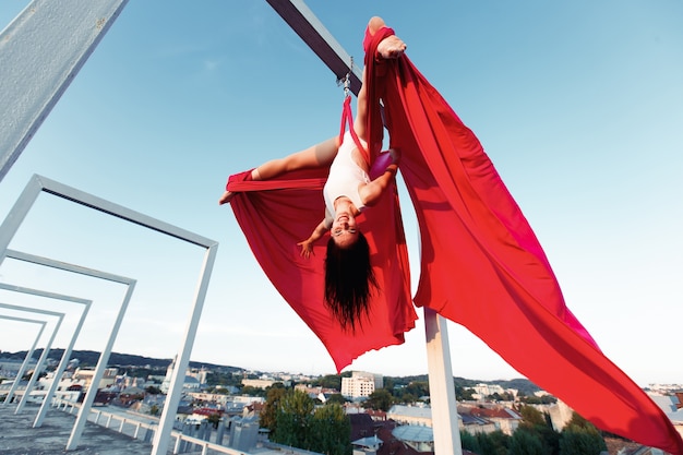 Dançarina sexy que executa dança aérea no telhado ao pôr do sol Foto gratuita