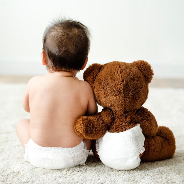 De volta de um bebê com um ursinho de pelúcia Foto Premium