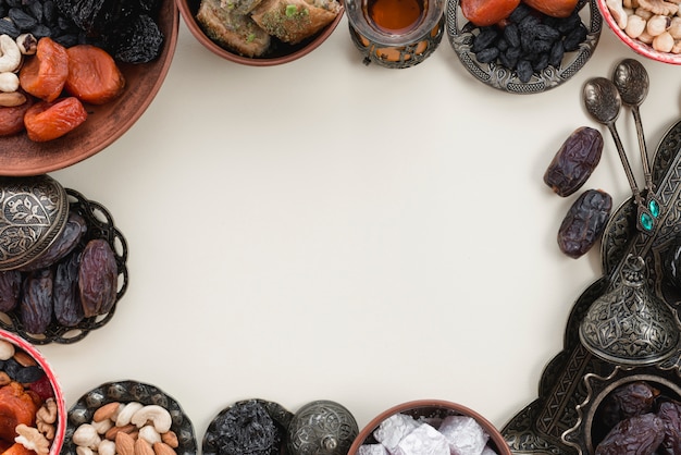 Decoração de feriados orientais com frutas de datas; datas; lukum e nozes no fundo branco com espaço no centro para escrever o texto Foto gratuita
